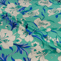 Floral fabric with blue and white flowers on a teal background