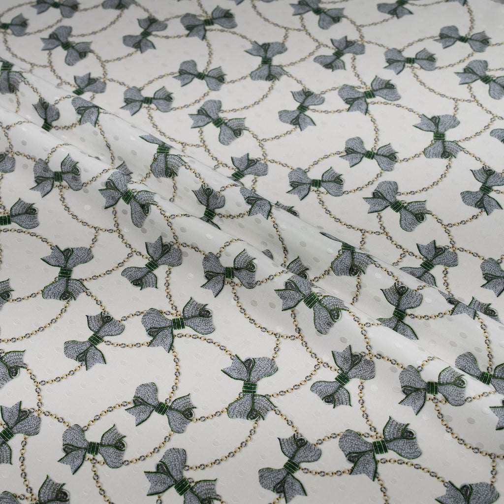 Patterned fabric with small bows and chain designs on a white background