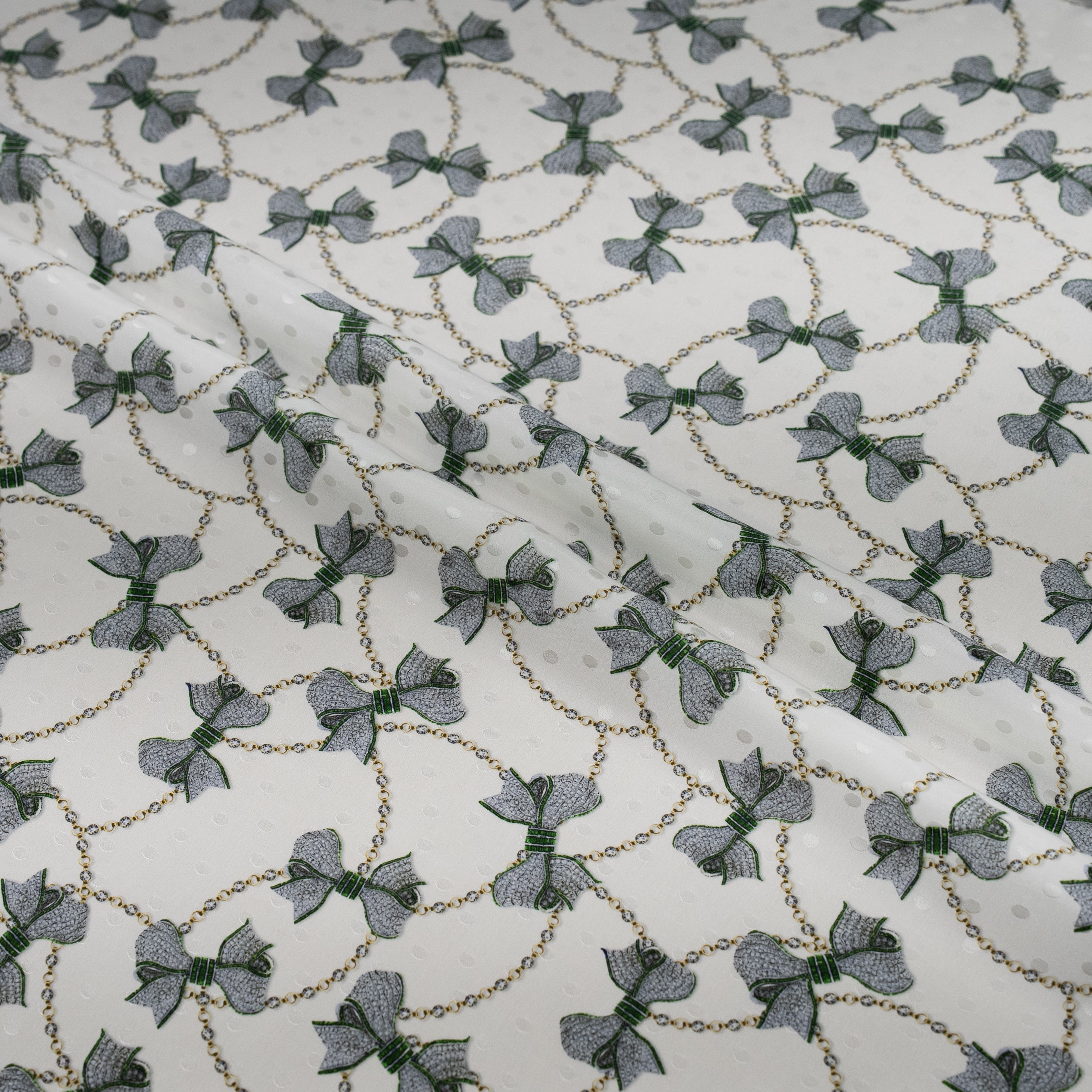 Patterned fabric with small bows and chain designs on a white background