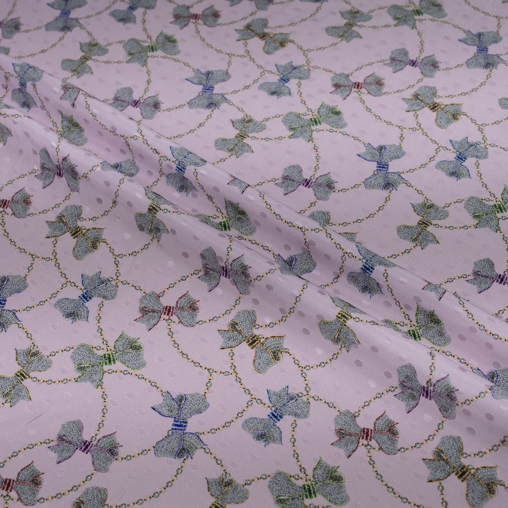 Fabric with a pattern of green bows and gold chains on a white background