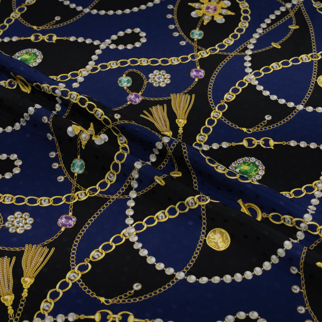 Decorative fabric with gold chains, pearls, and gemstones on a blue background