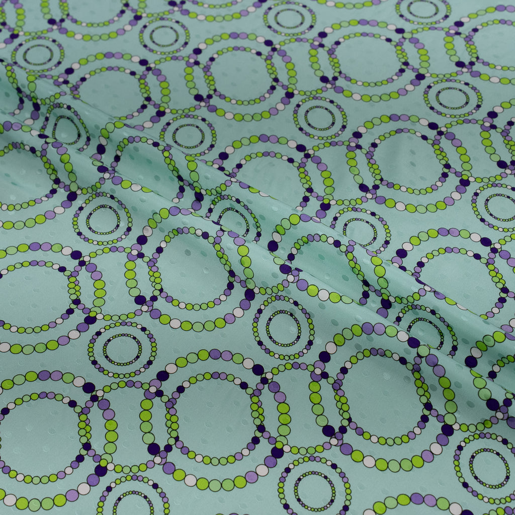 Pattern of interlocking circles in green and purple on a teal background