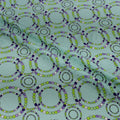 Pattern of interlocking circles in green and purple on a teal background
