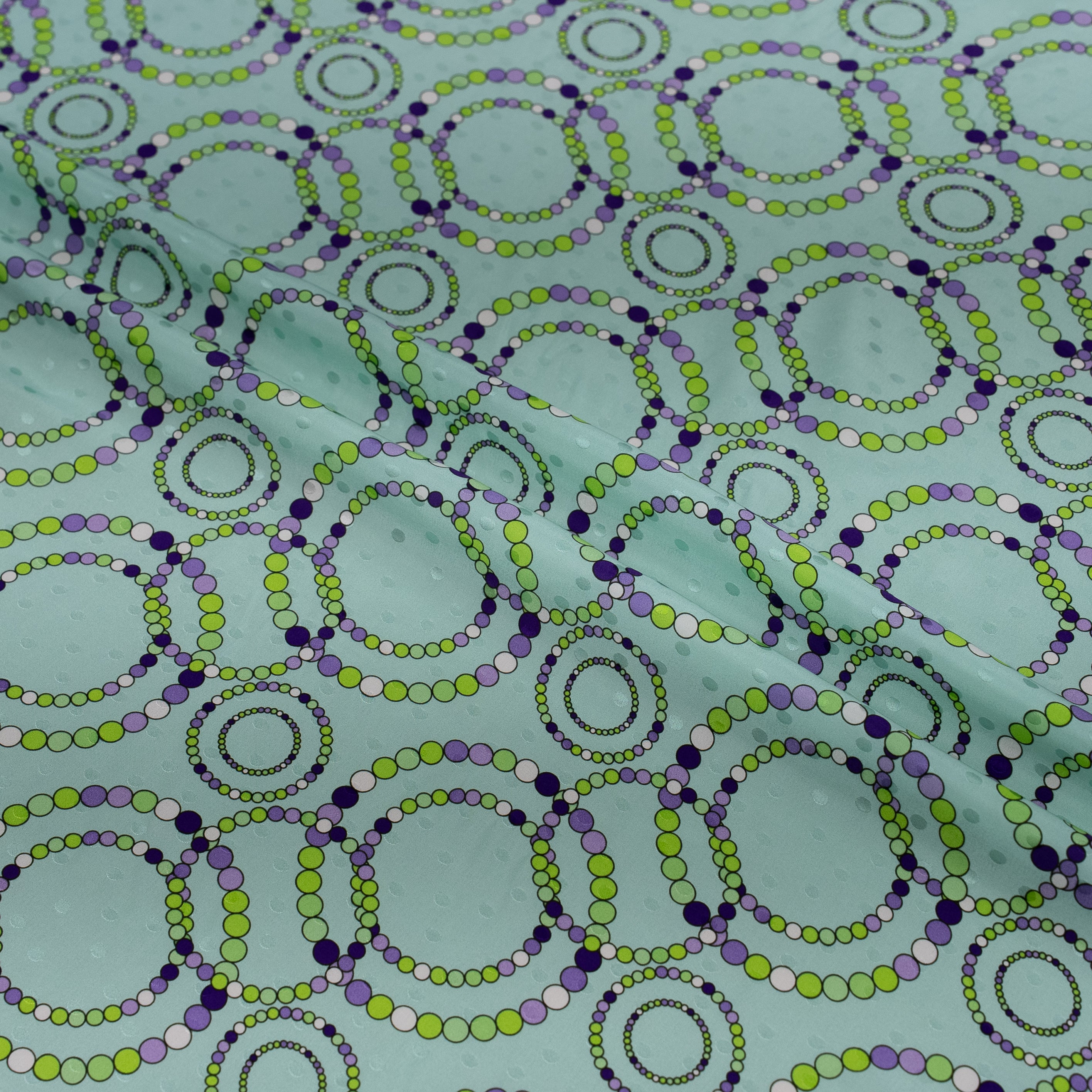Pattern of interlocking circles in green and purple on a teal background