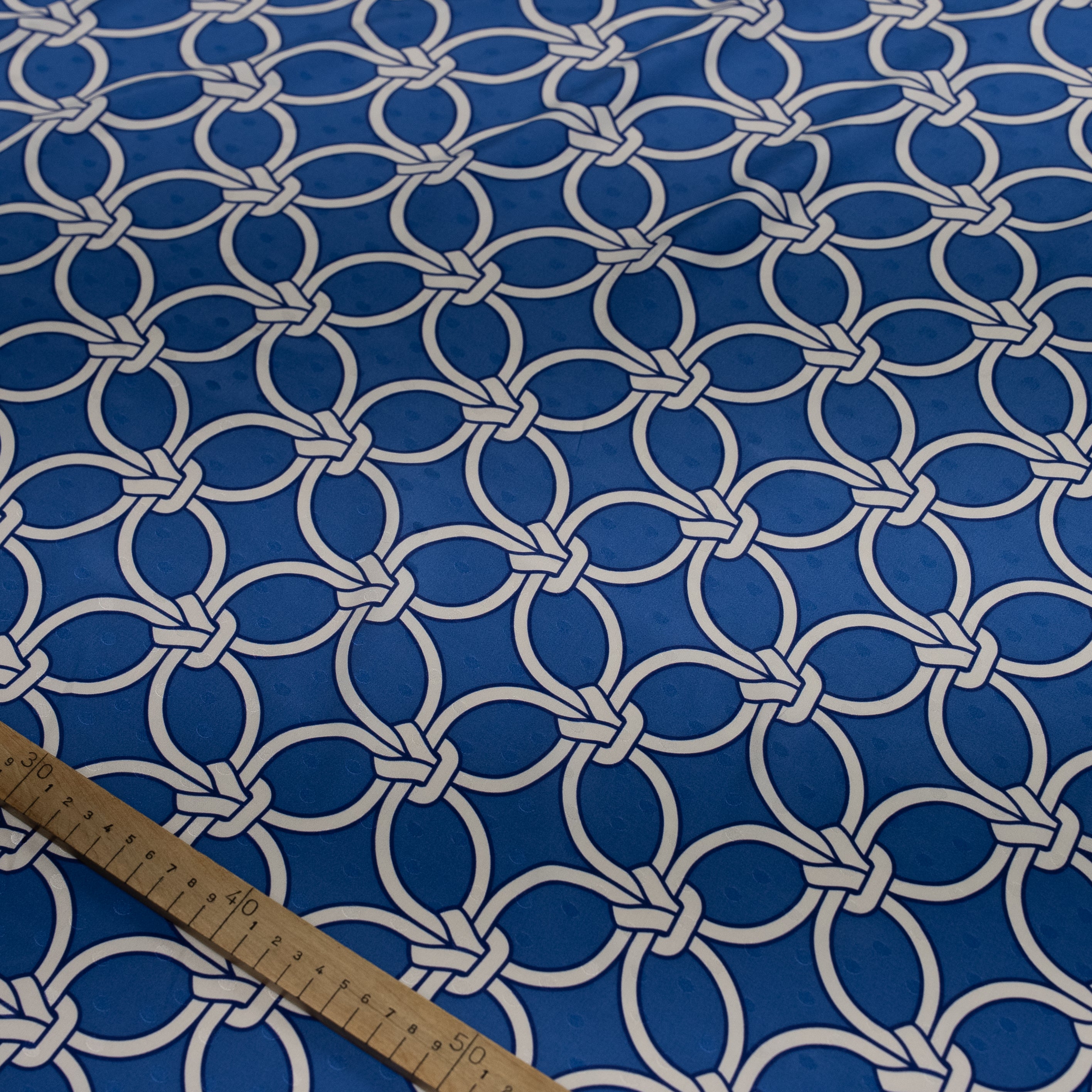 Blue fabric with white geometric pattern and a ruler for scale