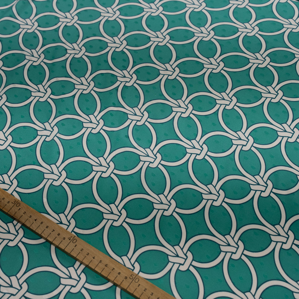 Teal fabric with white geometric pattern and wooden ruler for scale