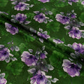 Fabric with purple floral pattern on a green background