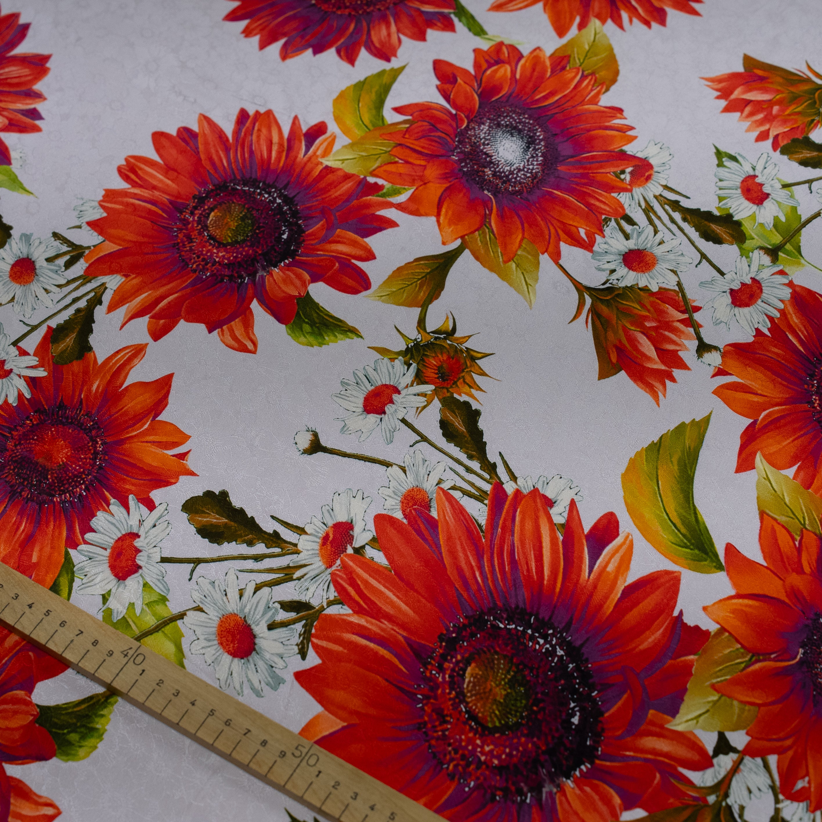Floral fabric pattern with sunflowers and a ruler for scale on a white background