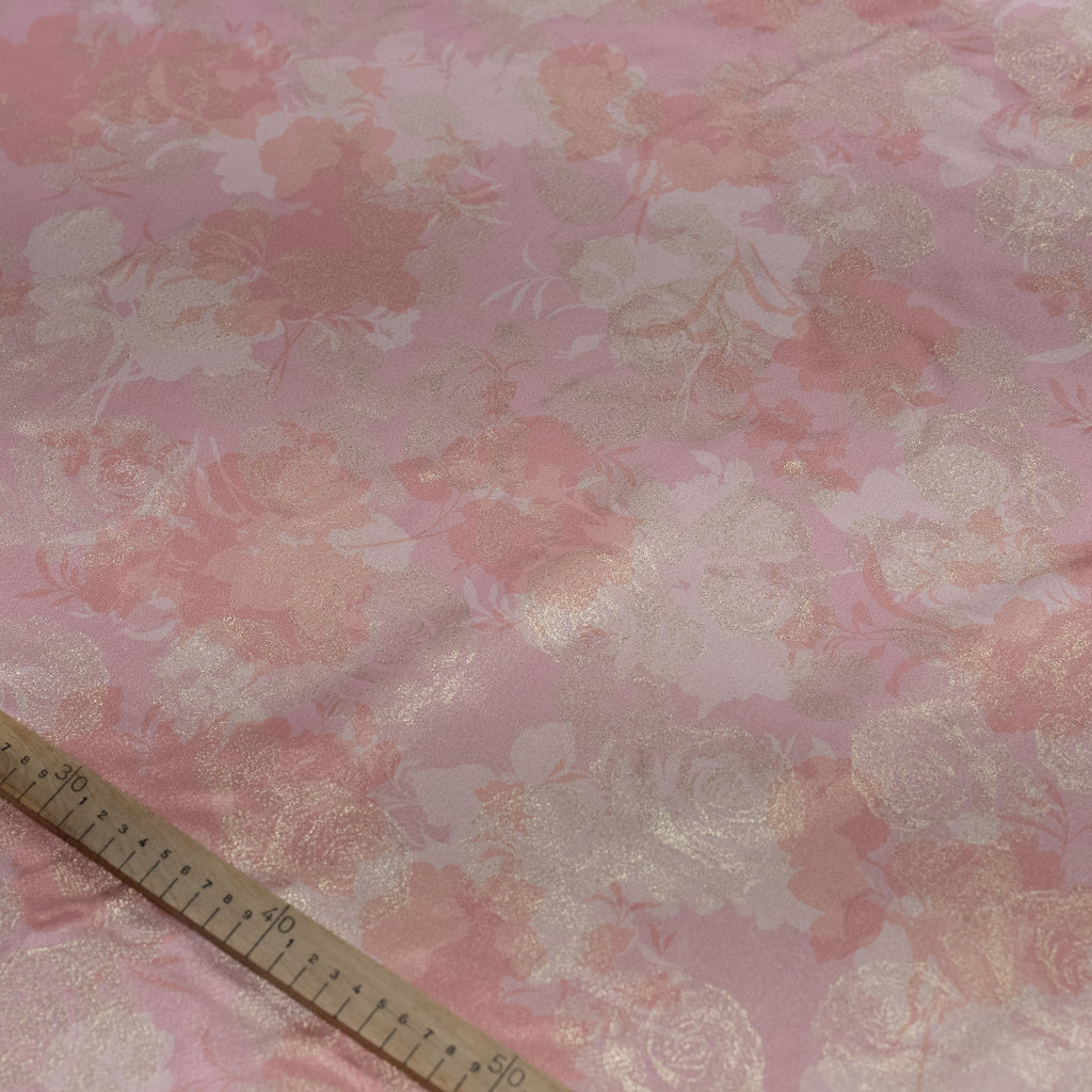 Floral patterned fabric with a ruler for scale on a pink background