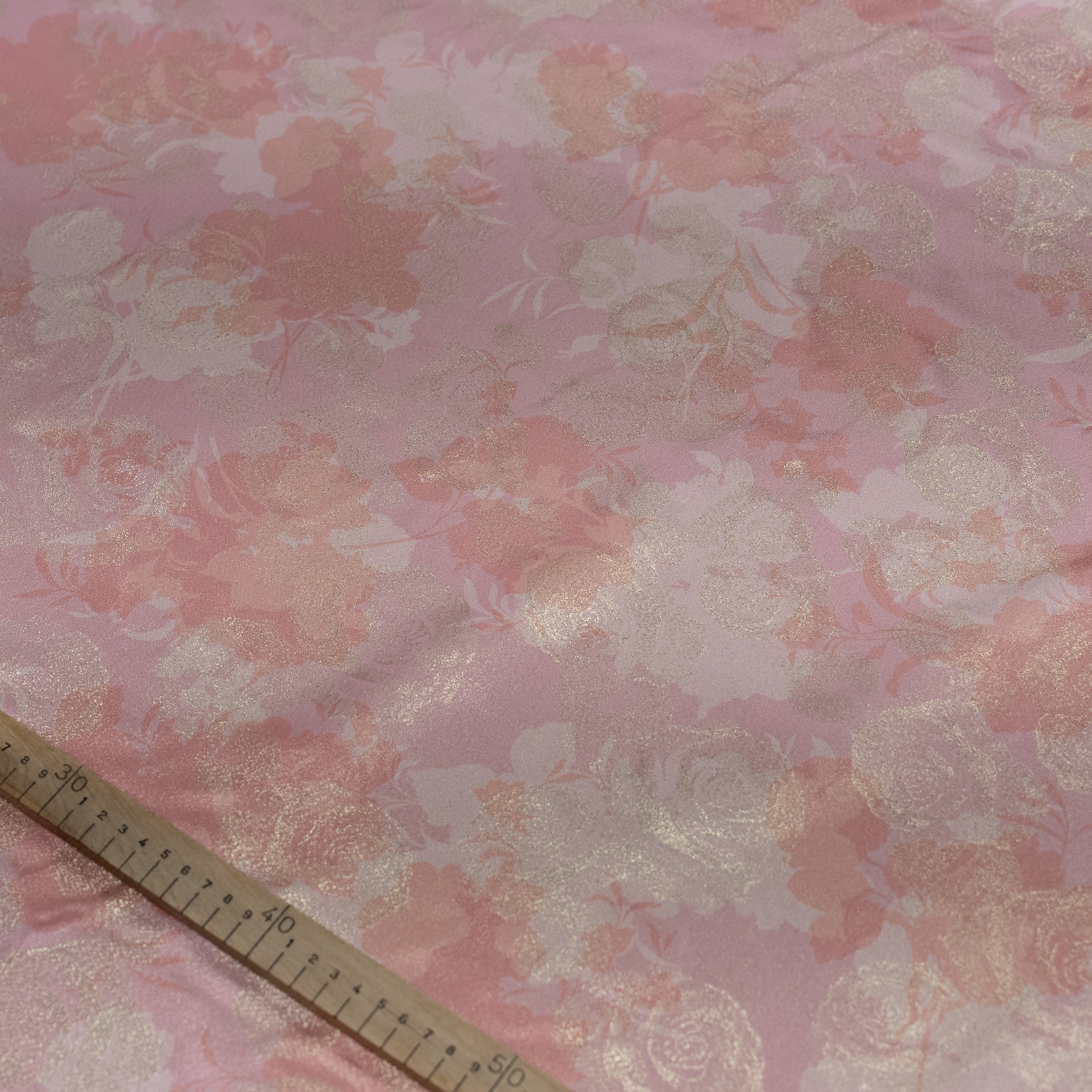 Floral patterned fabric with a ruler for scale on a pink background