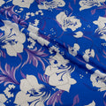 Floral patterned fabric with white flowers and purple accents on a blue background