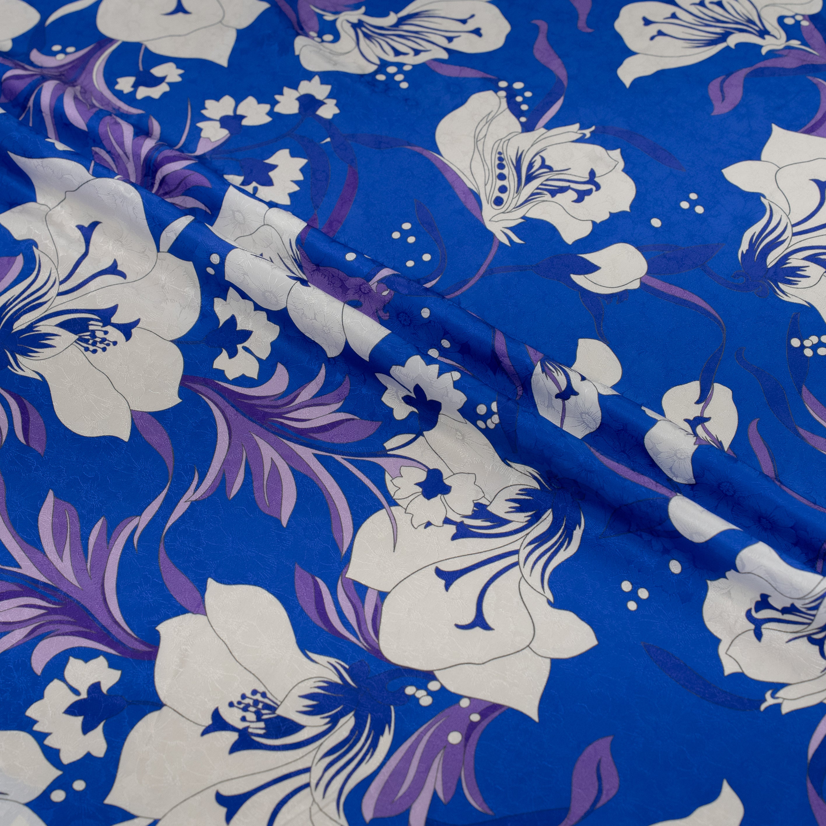 Floral patterned fabric with white flowers and purple accents on a blue background